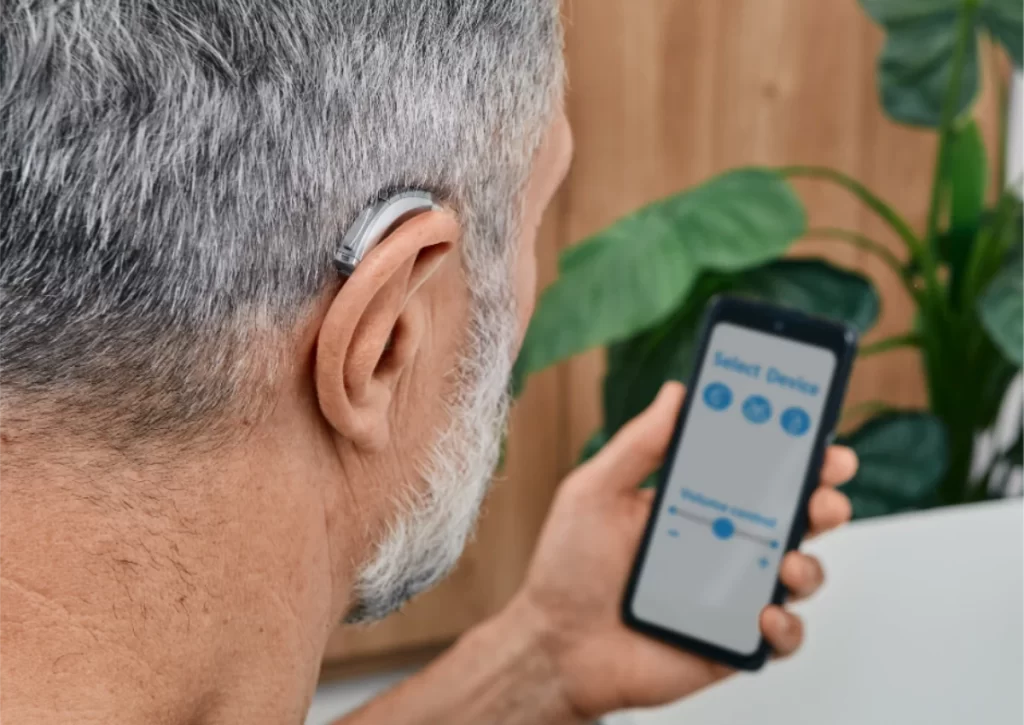 Man wearing hearing aid holding phone