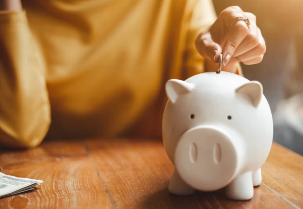 woman putting coins in piggy bank Rebates for hearing aids