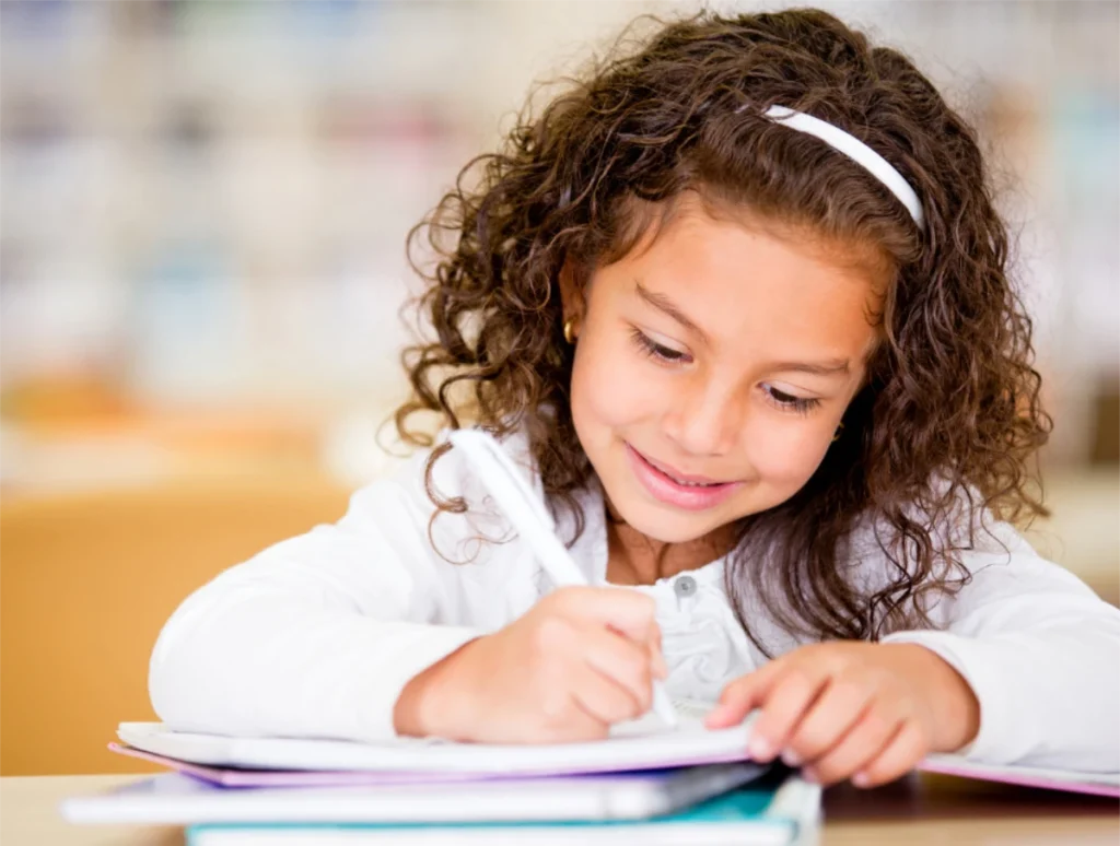 Child writing in school book-Signs of Hearing Loss Child writing in school book-Signs of Hearing Loss